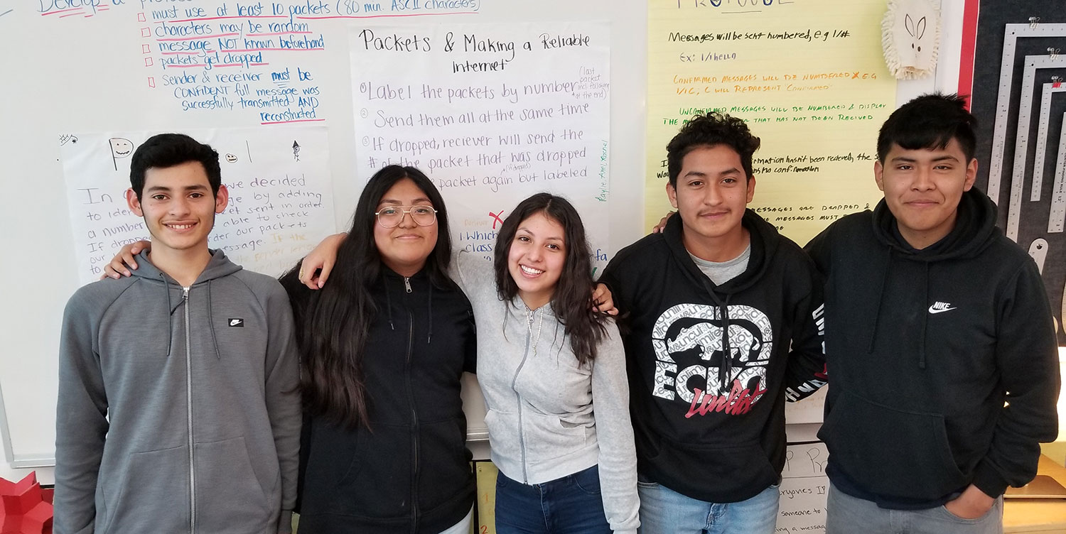 Computer Science students standing by the board